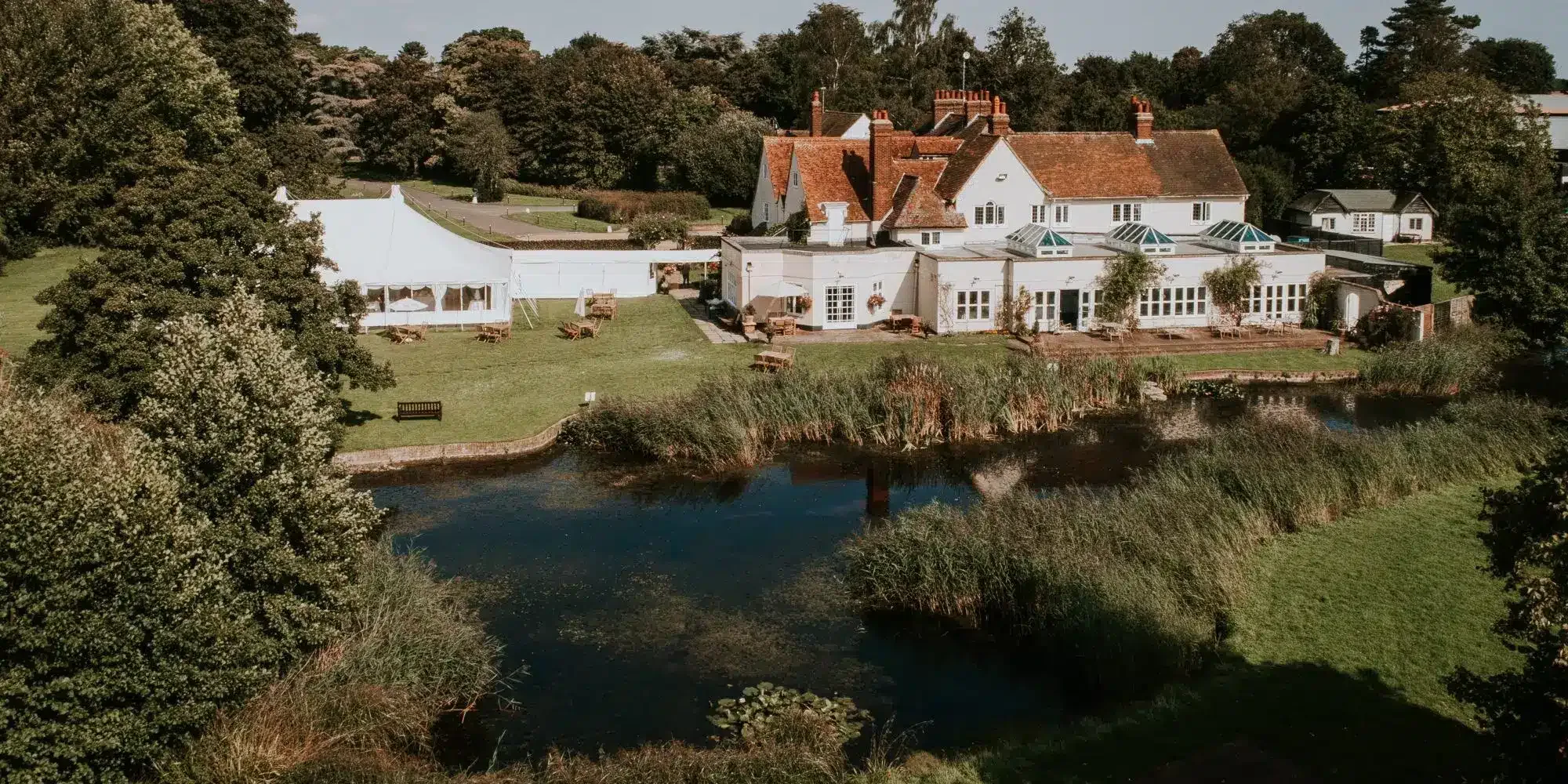 Prested Hall and its moat, seen across the grounds at Feering, Essex